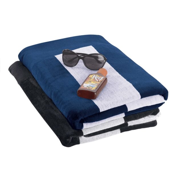 Three folded beach towels in blue, white, and black stripes are stacked. A bottle of tanning oil and a pair of black sunglasses rest on top.