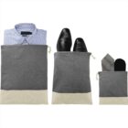 Three gray travel pouches holding a shirt, shoes, and a necktie with socks.