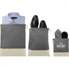 Travel pouches holding a folded shirt, dress shoes, and a folded tie with socks.