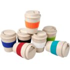 Seven reusable coffee cups are stacked together, each with a different colored silicone grip: blue, red, green, white, black, and brown. The cups have beige lids and bodies, and are arranged in a semi-circle.