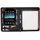 An open black portfolio case displaying a tablet on the left, secured with elastic straps, a pen in a holder, and a lined notepad on the right. Small pockets contain USB drives and business cards.