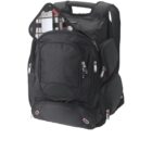 A black backpack with multiple compartments and silver zippers, featuring an open section at the top revealing plaid fabric and a small electronic device inside. The bag has padded shoulder straps and a sturdy handle.