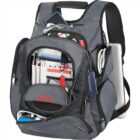 A gray and black backpack with multiple compartments, including a front pocket with organized stationary items, a passport, and a tablet. The side compartment holds a partially visible laptop.