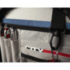 Close-up of a gray backpack with pen slots on the side. Three pens with red and silver accents are visible. A blue strip and carabiner are attached nearby. A mesh pocket and white stitching are part of its design.