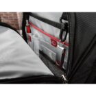 Interior of a black backpack with multiple compartments and pockets. A red and silver USB drive is clipped inside. The lining is gray with red accents, and the open zipper reveals the organized storage space.