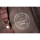 Close-up of a brown fabric bag featuring a leather strap with a metal buckle. The bag displays a circular logo that reads Vintage Cotton Field & Co Collection stamped in white.