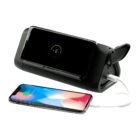 A black charging device simultaneously wirelessly charges one smartphone and another via USB cable. The phone on the left shows a charging notification with 57%, and the phone on the right displays a colorful screen.