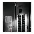 A flashlight illuminates an open electrical breaker panel with multiple switches. The panel has labeled sections and some handwritten notes. The surroundings are dark, highlighting the concentrated light on the breakers.