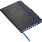 A black notebook with embossed text on the cover reading hello, goodbye. It is bound with a blue elastic band, and has a blue ribbon bookmark. A pen is attached to the side.
