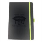 A black notebook with a green elastic band and pen holder. The cover features a glossy lip design with the words GlossTone and High-Impact Branding.