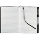 An open lined notebook with a black ribbon bookmark draped across the pages. A silver pen is secured in a holder on the right side of the notebook. The notebook cover is black.