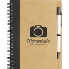 A spiral-bound notebook with a brown cover featuring a black camera logo and the text Momentado Photography. A black and white pen is attached to the right side of the notebook.