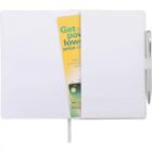 Open notebook with a yellow brochure partially tucked inside. A pen is placed in a holder on the right side, and a ribbon marker is visible in the center.
