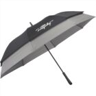 A large black and gray umbrella with a black handle is open, displaying a logo with cursive text and a graphic of an airplane on one panel. The umbrellas design appears sleek and sturdy.