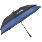 A large blue and black umbrella with a curved handle is open, showing a logo or design on the top panel. The umbrella features a sturdy frame and a layered design for added strength and coverage.