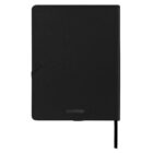 A closed black notebook with a textured cover and a thin black ribbon bookmark. The word Scriptura is embossed on the bottom front cover.