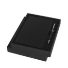 A black leather notebook and pen set in an open black gift box. The notebook cover is sleek and textured, and the pen has silver accents. The items are neatly arranged within the box, which rests on its slightly open lid.