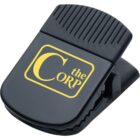 A black plastic clip with a ribbed grip on top and a wide jaw. It features a yellow logo with the words The Corp printed on the front.