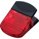 A red and black plastic clip with a ribbed black handle and a translucent red gripping section. The clip includes a small metal spring mechanism for opening and closing.