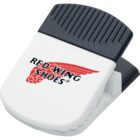A white and black magnetic clip with the Red Wing Shoes logo in red and black on the front. The top has a black grooved grip, and the clip resembles a binder clip with a ridged white section for holding items.