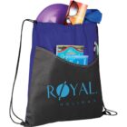 A blue and black drawstring bag labeled Royal Holiday is filled with a purple disc, sunglasses, a book, and blue fabric. The front pocket holds a magazine, a pen, and other small items.