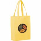 A yellow tote bag with two handles, featuring a black circle in the center with an orange and a green leaf design.