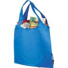 A blue reusable shopping bag filled with groceries, including cereal boxes and snack bars, is shown standing upright. The bag has a simple, foldable design with two handles and a small drawstring pocket at the bottom corner.
