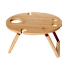 A round wooden picnic table with three holes and one notch on the edge for holding wine glasses or bottles. It has foldable legs for portability and is designed for outdoor use.