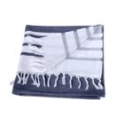 Folded woven blanket with alternating navy and white stripes, featuring fringe tassels along the edge. One corner is flipped over to reveal the pattern on both sides.