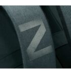 Close-up of a backpack strap with a large, light gray letter Z printed on a dark fabric. The texture is smooth, and the background is blurred.