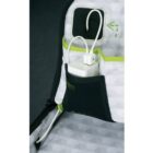A close-up of a tents interior showing a pocket with a black border containing a white power bank. Two cables are plugged into the power bank, one lying loose, against a white, patterned tent wall with green accents.