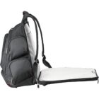 A black backpack with multiple compartments is shown fully opened. It features padded shoulder straps, red zipper accents, and a large main section that lays flat, revealing a white interior lining.