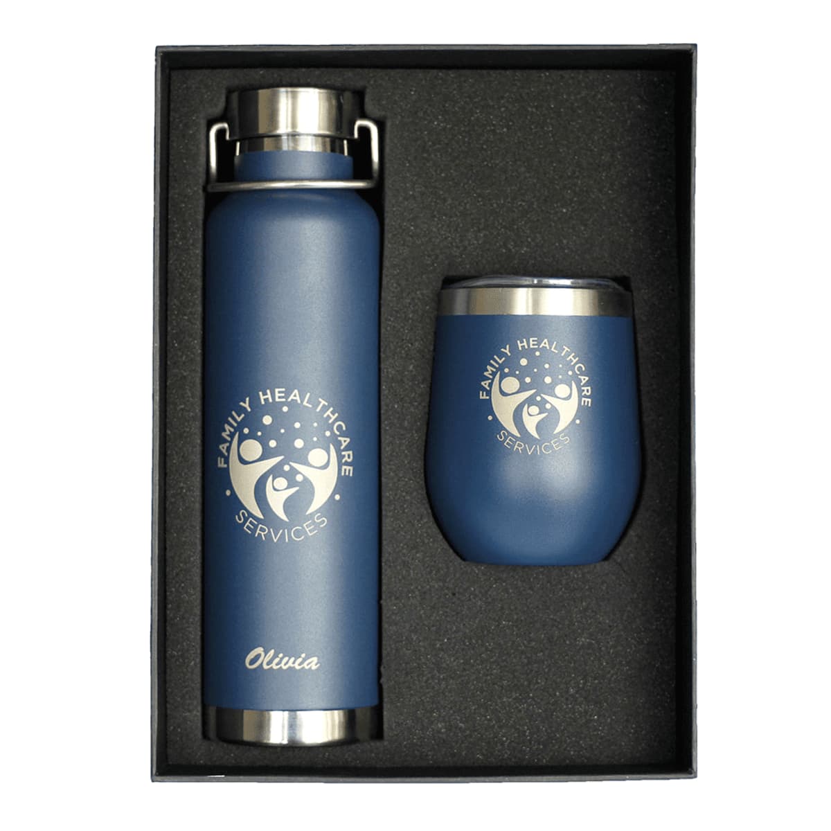 A gift set featuring a blue insulated bottle and a tumbler, both branded with Family Healthcare Services on a dark background. The name Olivia is engraved on the bottle. The set is neatly arranged in a box.