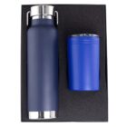 A gift set includes a navy blue insulated water bottle with a silver lid and handle, and a matching blue insulated cup. Both items are nestled in a black foam holder.