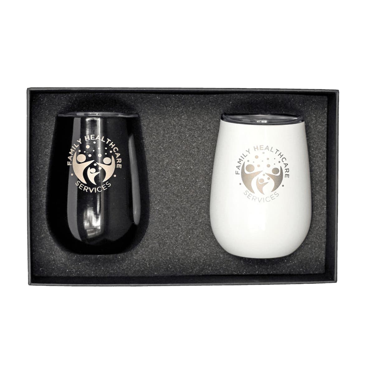 A black and a white insulated tumbler with lids, featuring a Family Healthcare Services logo. They are placed side by side in a black gift box with foam padding.