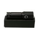 A black flashlight with a textured grip and a button on the side, placed on top of a black rectangular box.