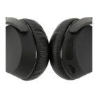 Close-up of black over-ear headphones with leather ear cushions. The control panel, featuring volume and power buttons, is visible on the right earcup. The headphones are positioned upright with earcups touching each other.