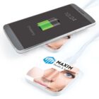 Smartphone wirelessly charging on a pad with a womans face and text MAXIM Health & Body.