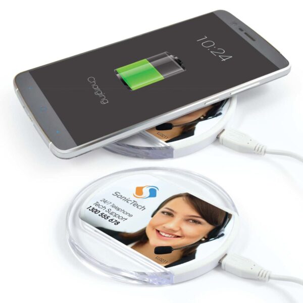 Smartphone charging wirelessly on a round pad with a printed headset image.