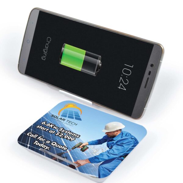 Phone wireless charging on a solar-themed charging pad with an advertising card.