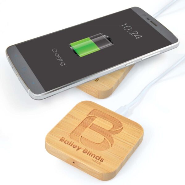 Smartphone charging on a wooden wireless pad with Bailey Blinds Ltd engraved.