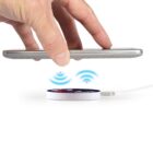 Phone hovered over a wireless charger emitting blue signals.