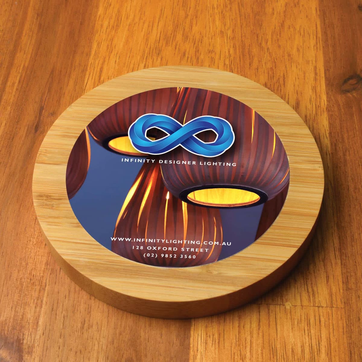 Round wooden block with Infinity Designer Lighting logo and contact information.