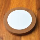 Round white coaster with a cork border on a wooden surface.