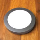 Round, modern LED ceiling light on a wooden surface.