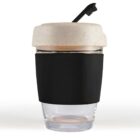 Reusable coffee cup with a black sleeve and cream lid, featuring a flipped-back tab.