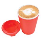 Red cup with latte art and matching red lid beside it.