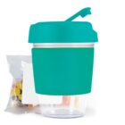 Turquoise snack cup with a straw, clear base, and a bag of colorful candy behind it.