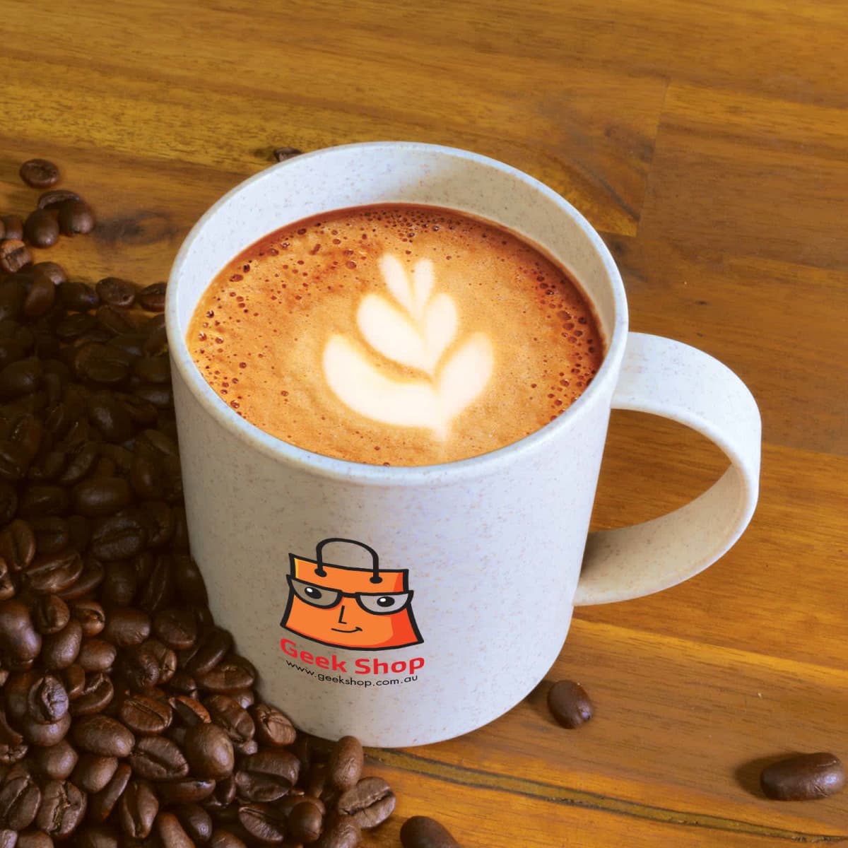 Coffee mug with leaf latte art, surrounded by coffee beans on a wooden surface.
