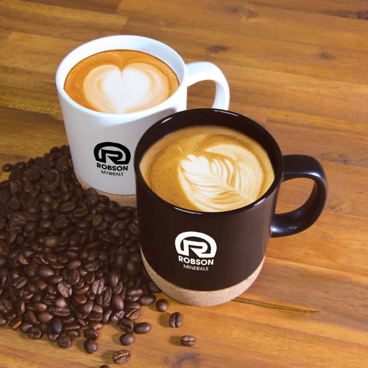Two mugs with latte art, surrounded by coffee beans on a wooden table.